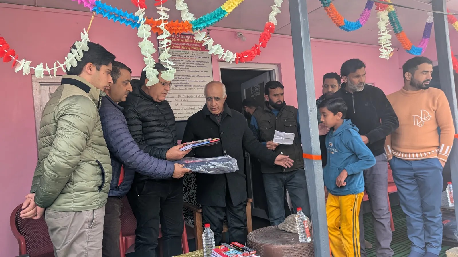 Guests handing a stationery kit and school bag to a student